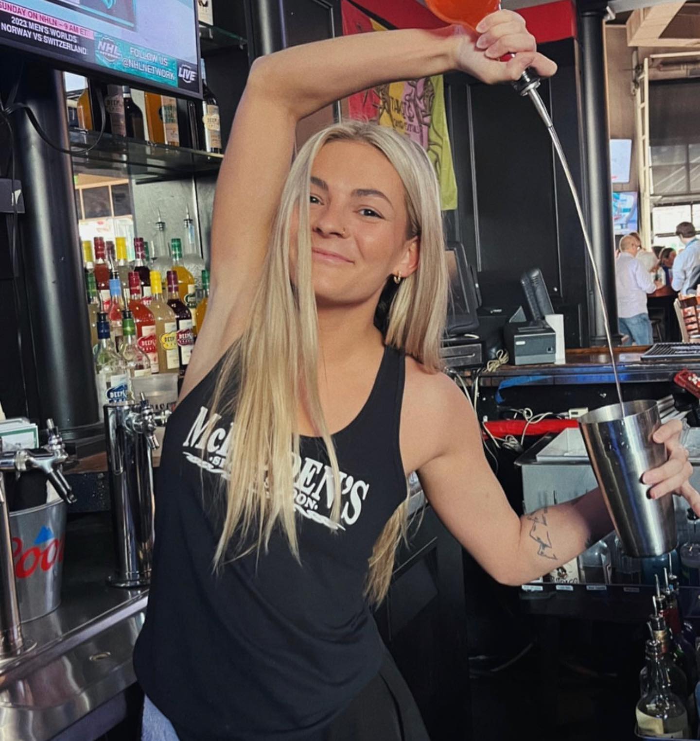 MaFadden's saloon bartender pouring a drink wearing her new merch
