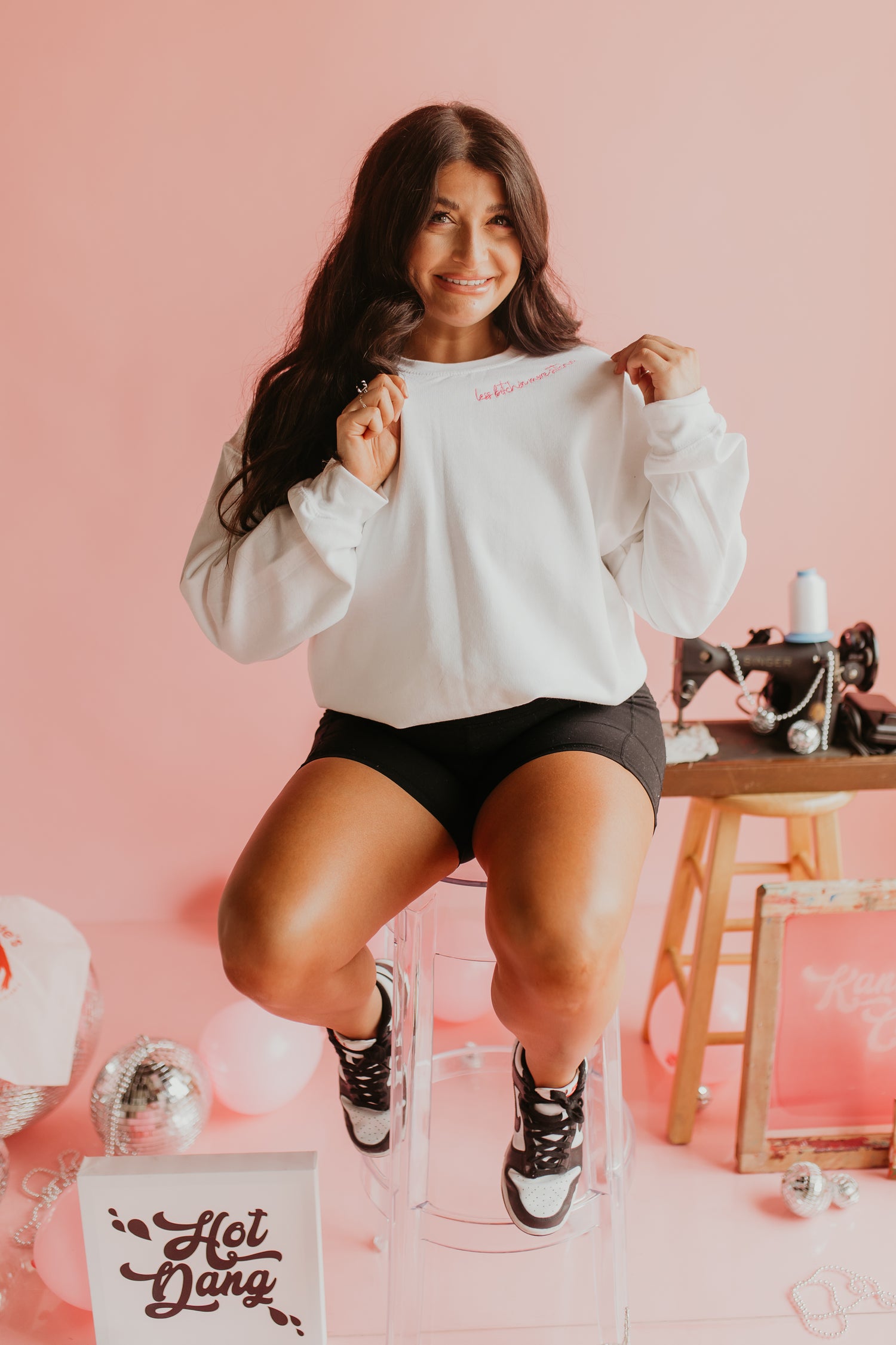 Leanna sitting on a stool wearing less bitchin', more stitchin' embroidered sweatshirt
