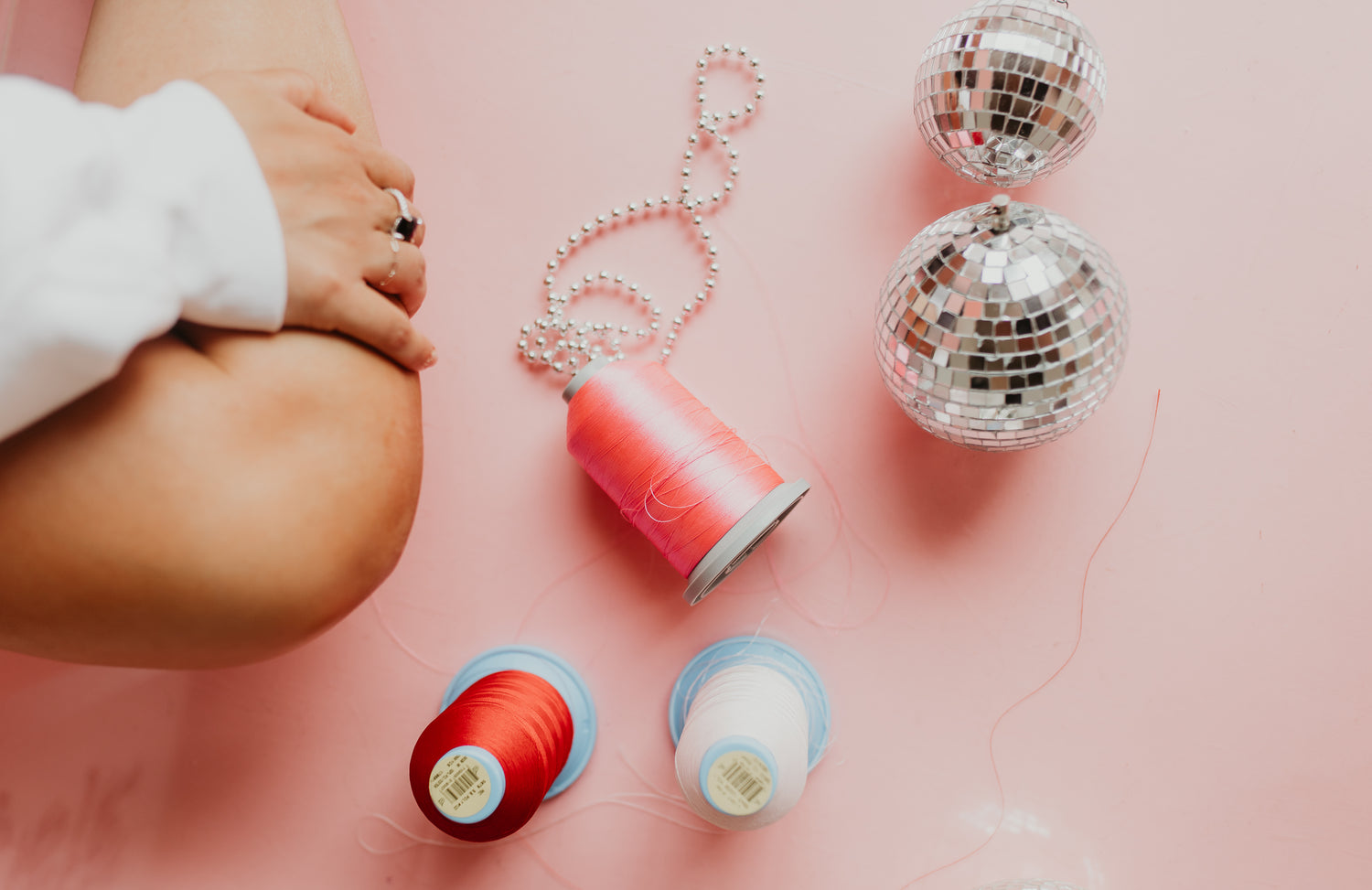 spools of pink, red, and white embroidered thread with pearls and disco balls