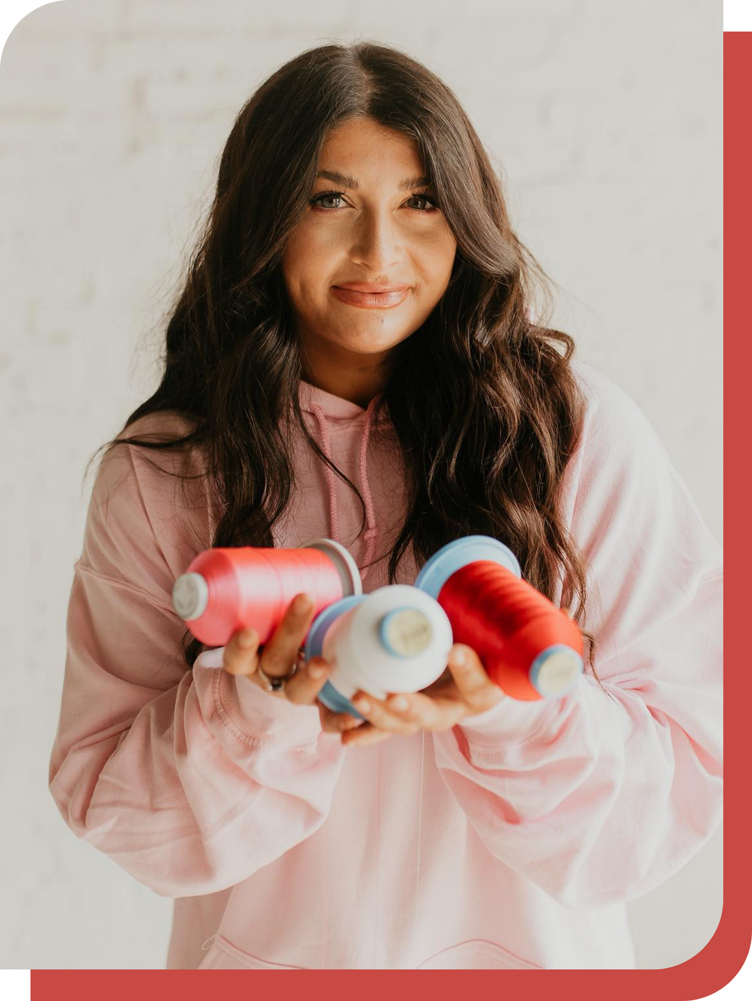Leanna, founder of Mazzeffe's, holding spools of pink, white, and red embroidery thread